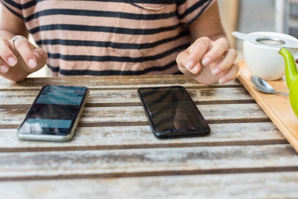 woman sharing info from one phone to another - Australian Stock Image