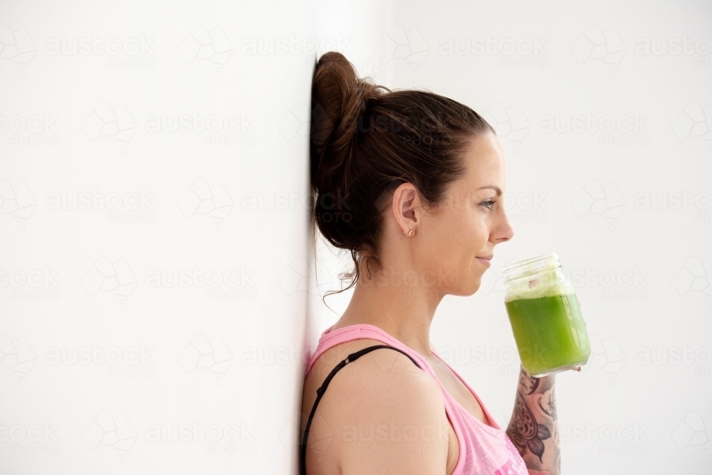 woman sipping green juice on white background - Australian Stock Image