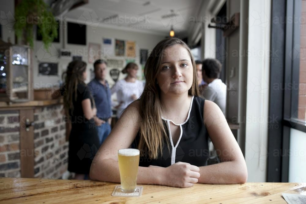 Woman sitting behind table at local craft beer bar - Australian Stock Image
