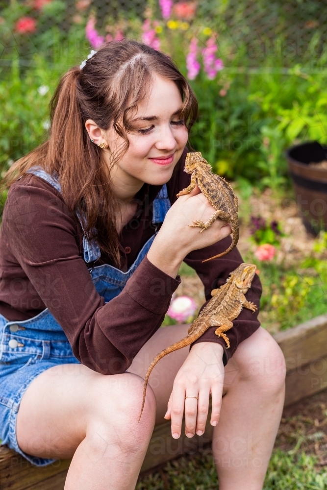 Woman sitting in garden with pet bearded dragon lizards - Australian Stock Image