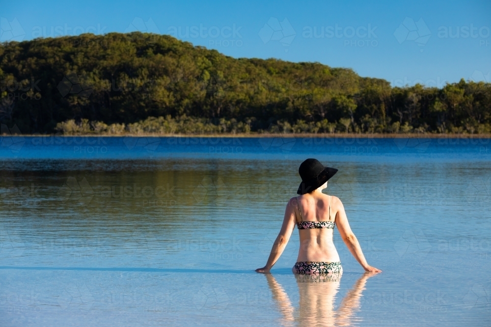 Woman sitting in water of a shallow lake on Fraser Island - Australian Stock Image