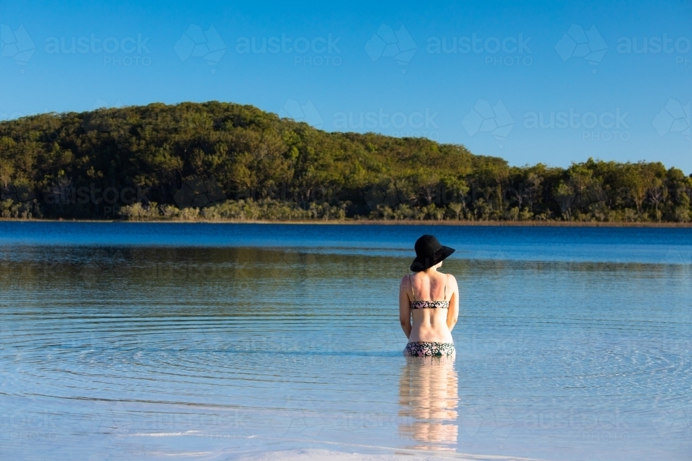 Woman sitting in water of a shallow lake on Fraser Island - Australian Stock Image