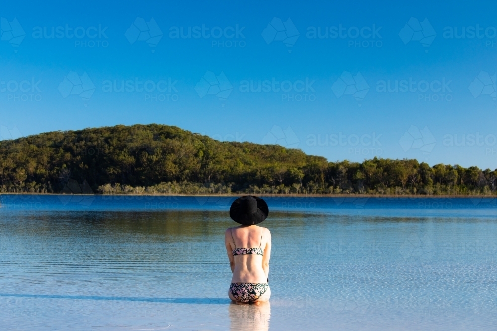 Woman sitting in water of a shallow lake on Fraser Island - Australian Stock Image