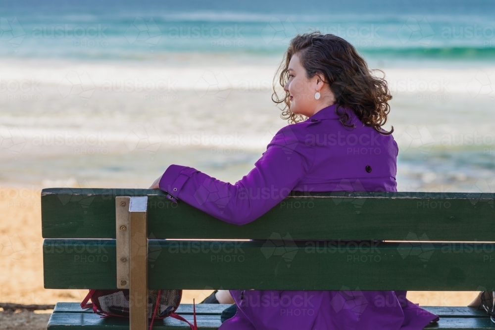 woman sitting on a bench by the sea - Australian Stock Image