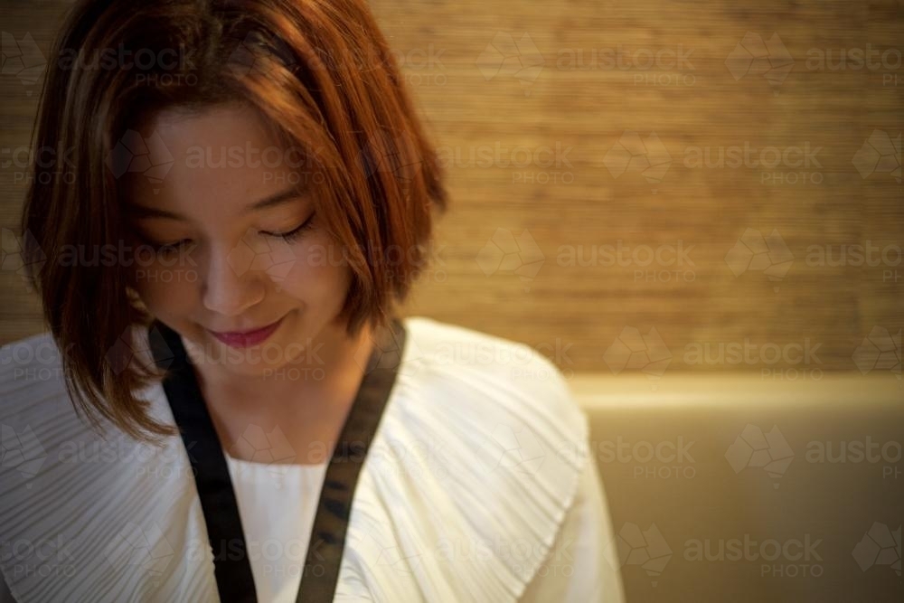 Woman sitting on a chair, looking down pensively - Australian Stock Image