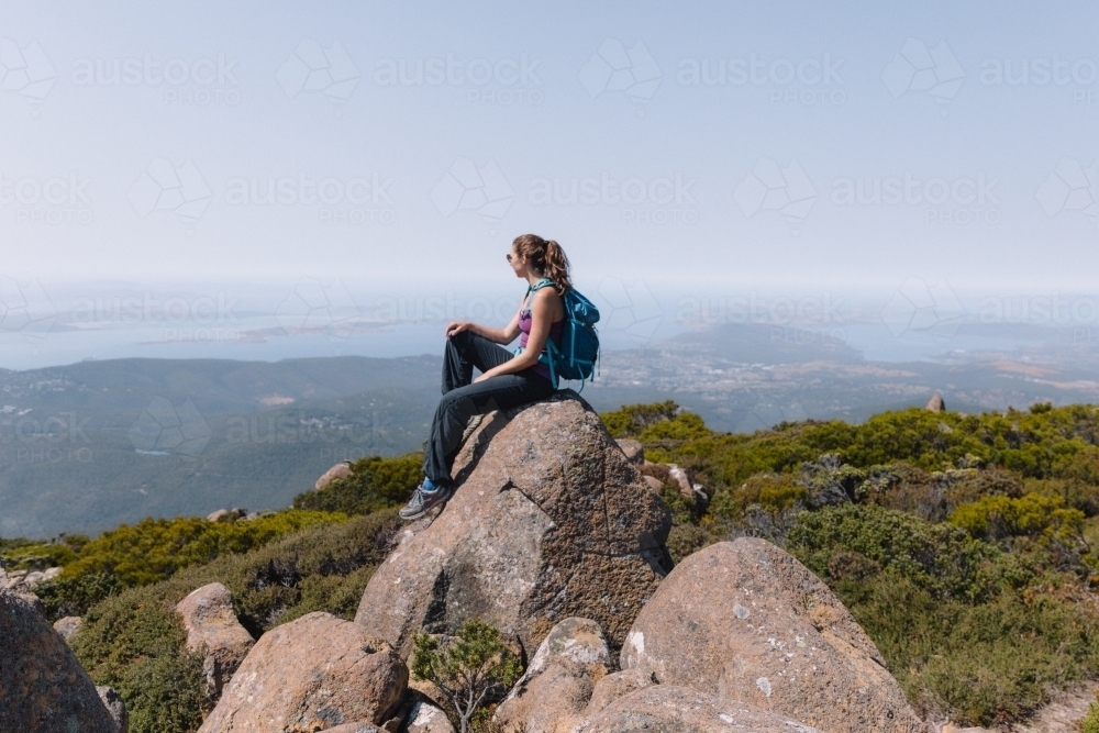 Woman sitting on a rock overlooking valley - Australian Stock Image