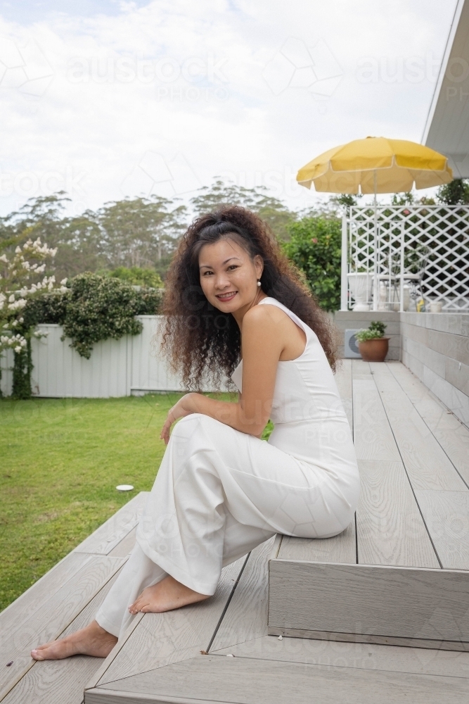 Woman sitting on backyard steps - Australian Stock Image