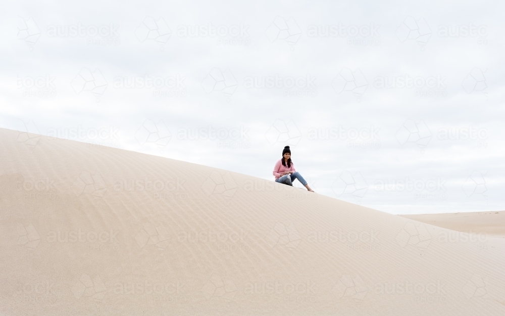 Woman sitting on sand dunes - Australian Stock Image