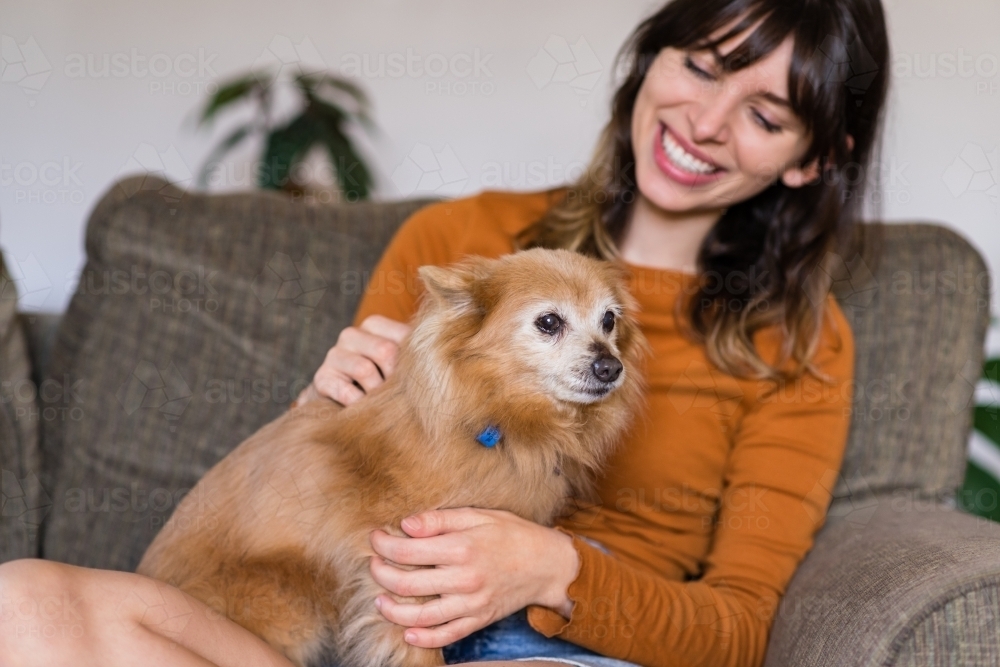 Image of woman sitting on sofa with her little dog Austockphoto