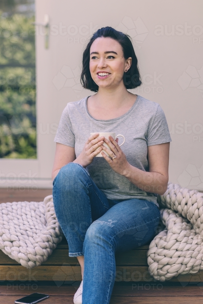 woman sitting outside enjoying a cup of tea - Australian Stock Image