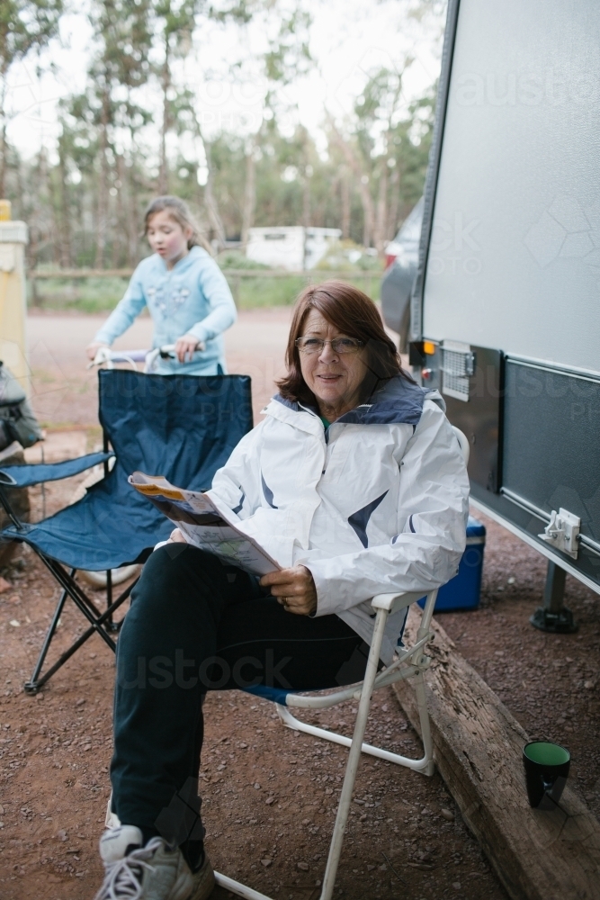 Woman sitting reading a magazine at a camp site - Australian Stock Image