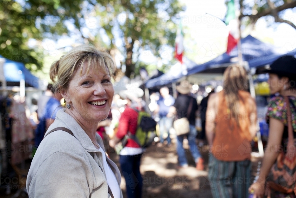 Woman smiling and walking through an outdoor market - Australian Stock Image