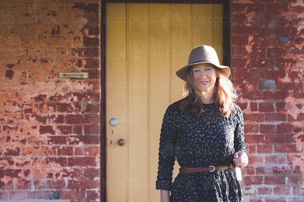 Woman smiling in front of a rustic house - Australian Stock Image