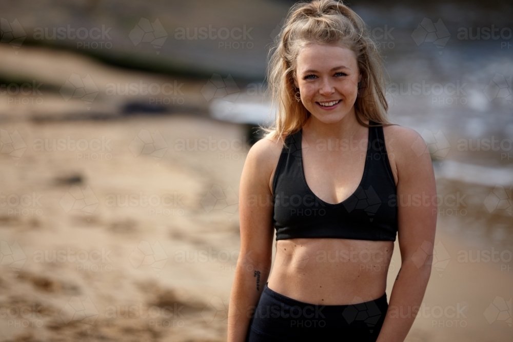 Woman smiling taking a break from exercise on beach - Australian Stock Image
