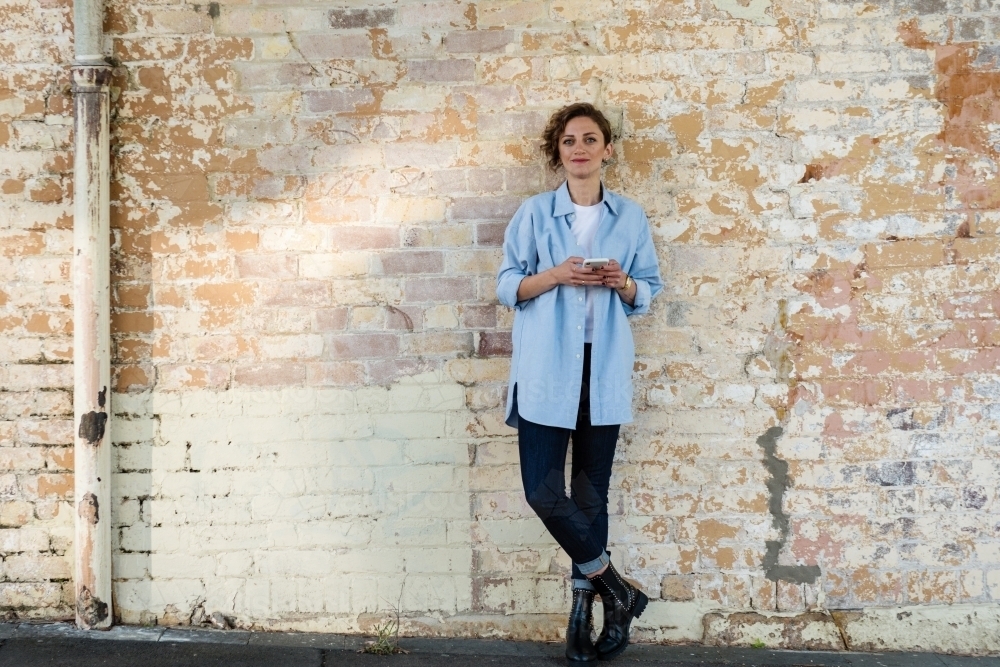 woman standing against brick wall - Australian Stock Image