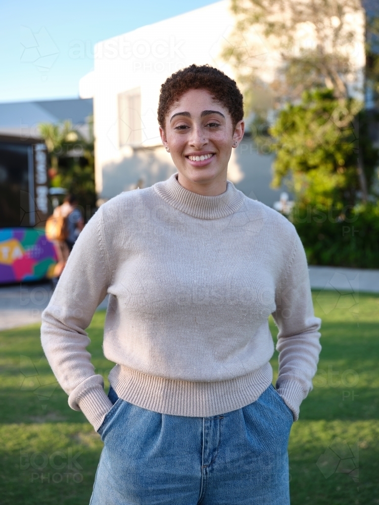 Woman standing in a park wearing a beige jumper - Australian Stock Image