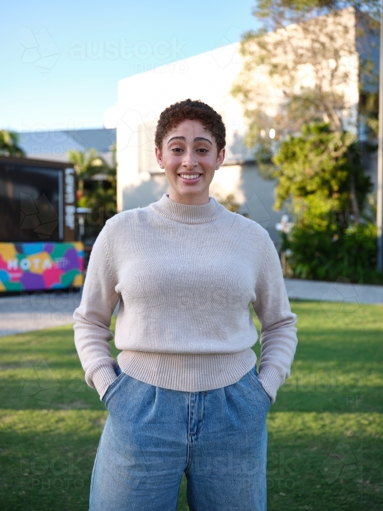Woman standing in a park wearing a beige jumper - Australian Stock Image