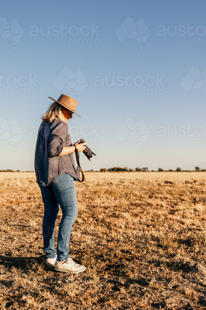 Woman standing looking down at camera outdoors on farm - Australian Stock Image