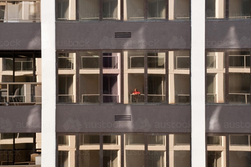 Woman standing on the balcony of a high rise apartment - Australian Stock Image