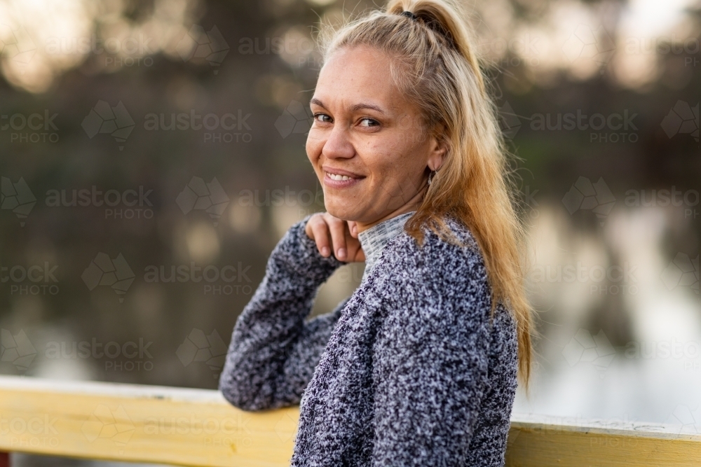 woman standing with chin on hand looking at camera - Australian Stock Image