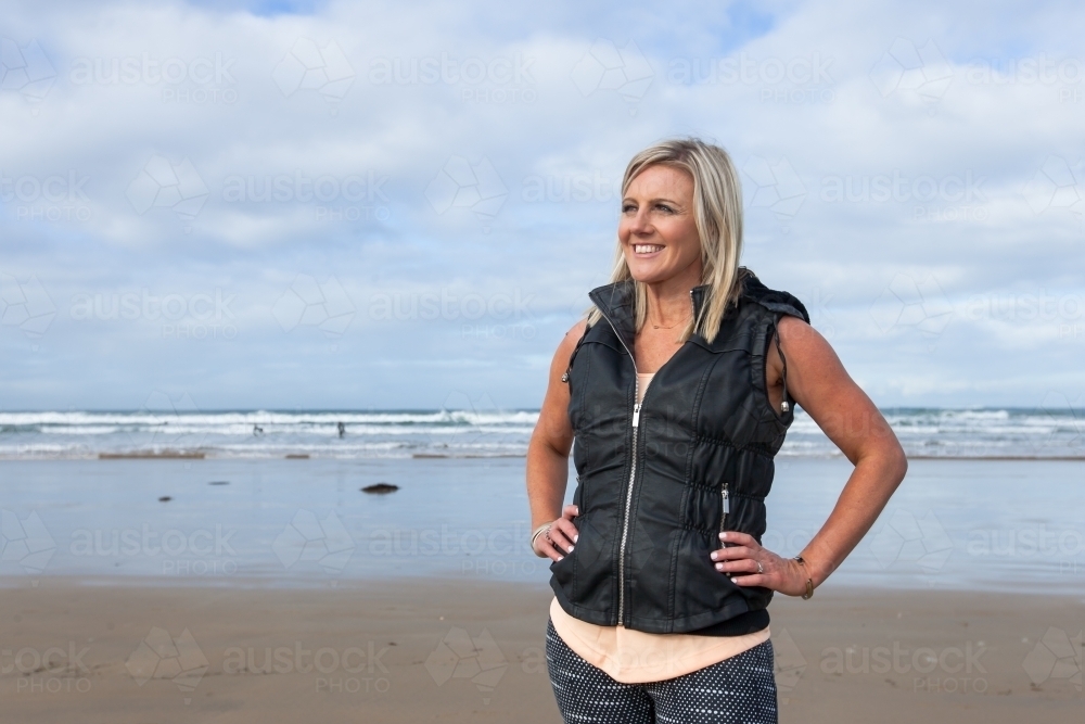 woman standing with hands on hips at the beach - Australian Stock Image