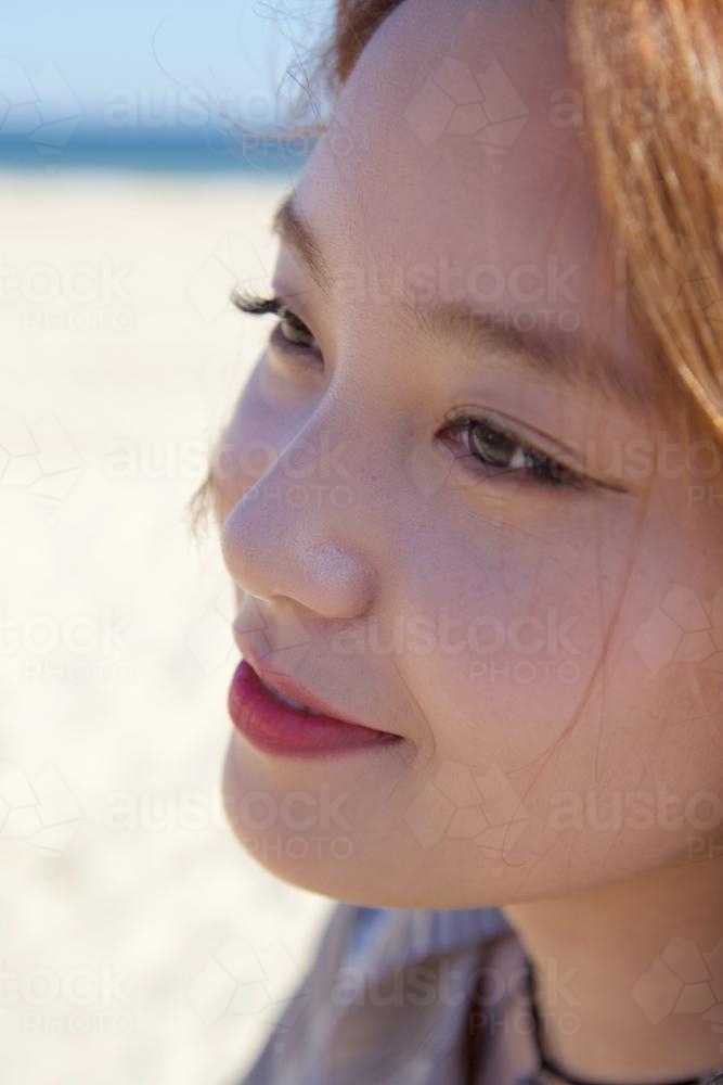 Woman staring pensively with the beach behind her - Australian Stock Image