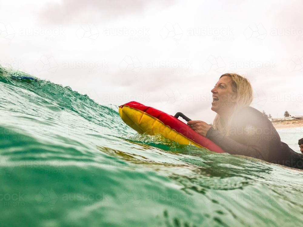 Woman surfing soft mat in ocean - Australian Stock Image