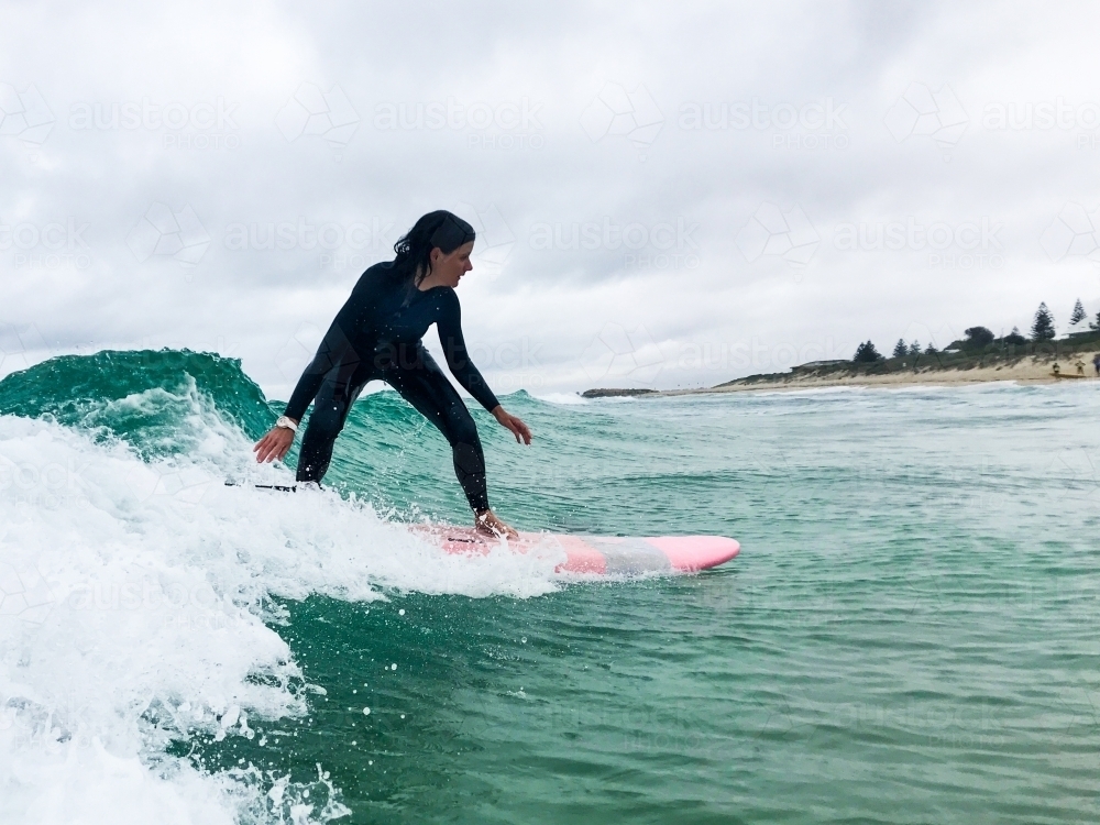 Woman surfing soft surfboard on wave - Australian Stock Image