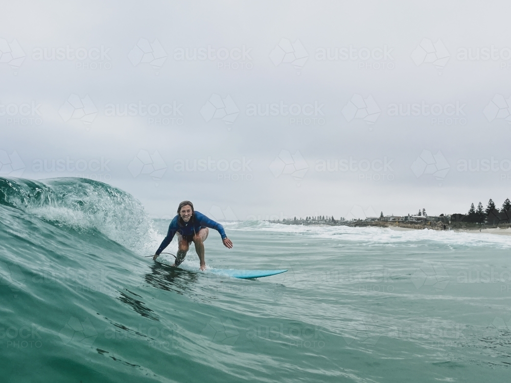 Woman surfing wave on fiberglass mid length board on overcast day - Australian Stock Image