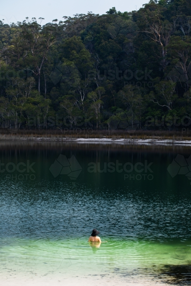 Woman swimming in a forest lined lake on Fraser Island - Australian Stock Image