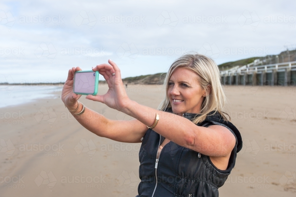 woman taking a photo at the beach - Australian Stock Image