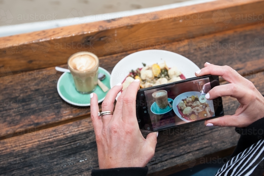 woman taking a photo of her breakfast at a cafe - Australian Stock Image