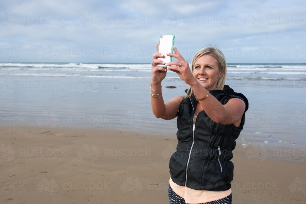 woman taking a selfie at the beach - Australian Stock Image