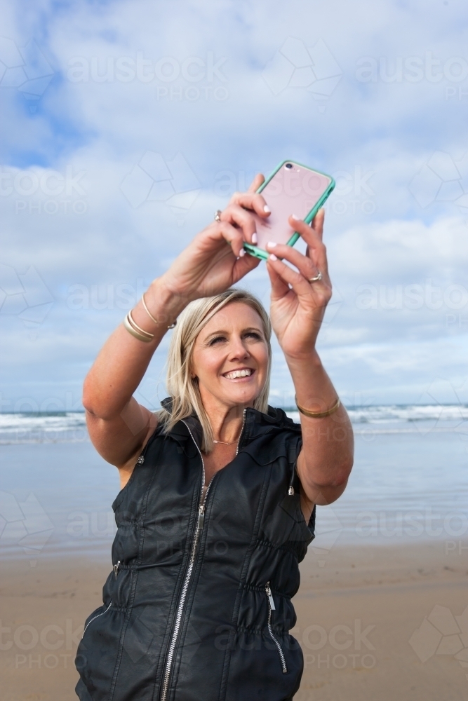 Woman taking a selfie at the beach - Australian Stock Image