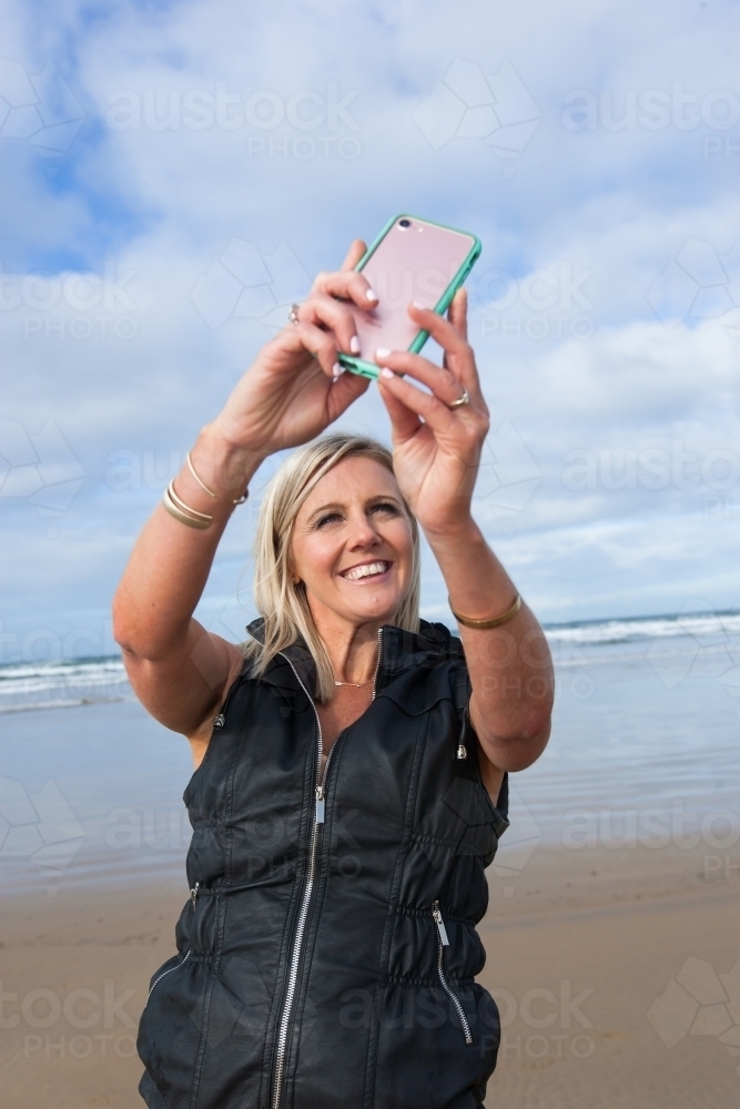 Woman taking a selfie at the beach - Australian Stock Image