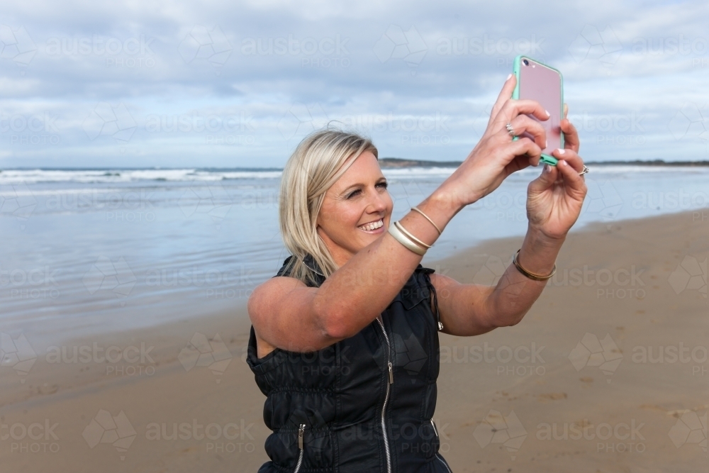 Woman taking a selfie at the beach - Australian Stock Image