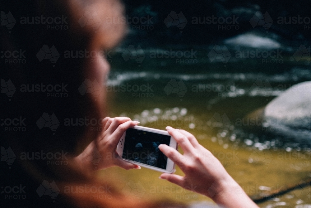 Woman taking photos with phone camera in Mossman Gorge - Australian Stock Image