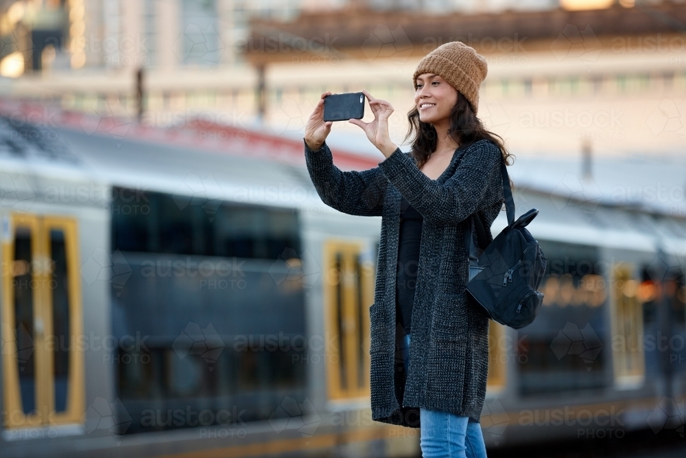 Woman talking photo with mobile phone at train station - Australian Stock Image