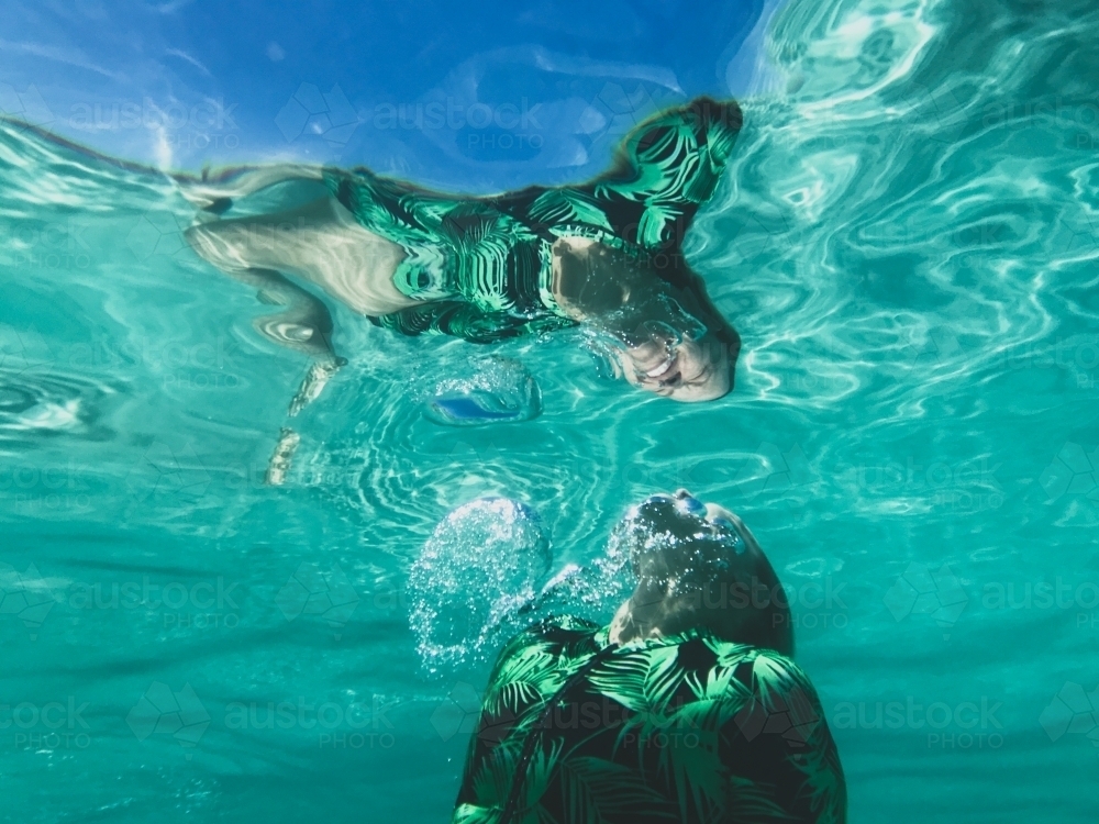 Woman underwater heading swimming to the surface - Australian Stock Image