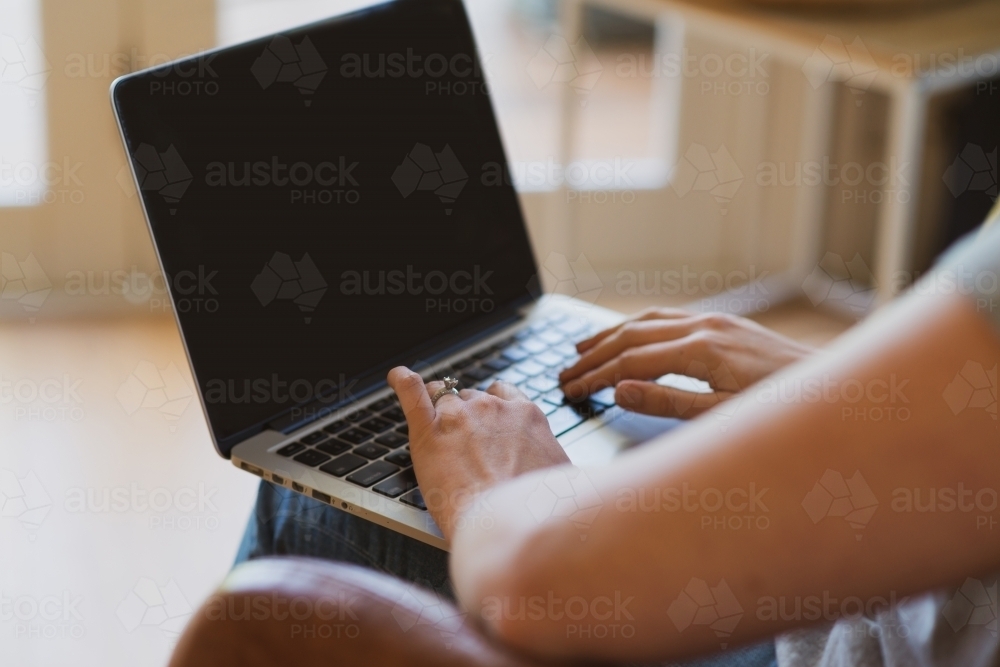 woman using laptop at home, sitting in chair - Australian Stock Image
