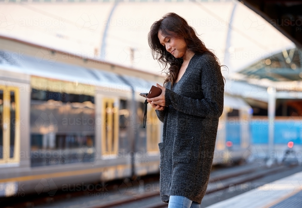 Woman waiting at train station with mobile phone - Australian Stock Image