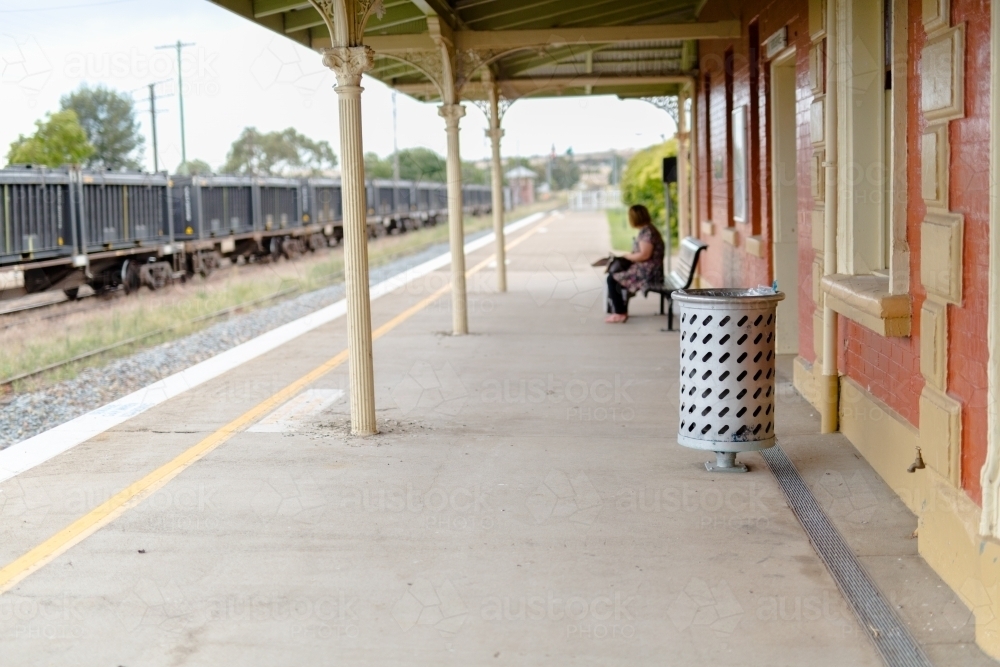 Woman waiting for a train at the platform of the Harden railway station - Australian Stock Image