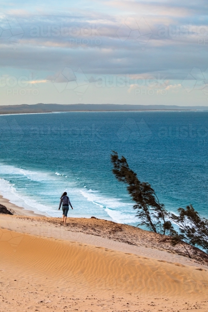 Woman walking along the sand dune of Carlo Sandblow  at dusk. - Australian Stock Image