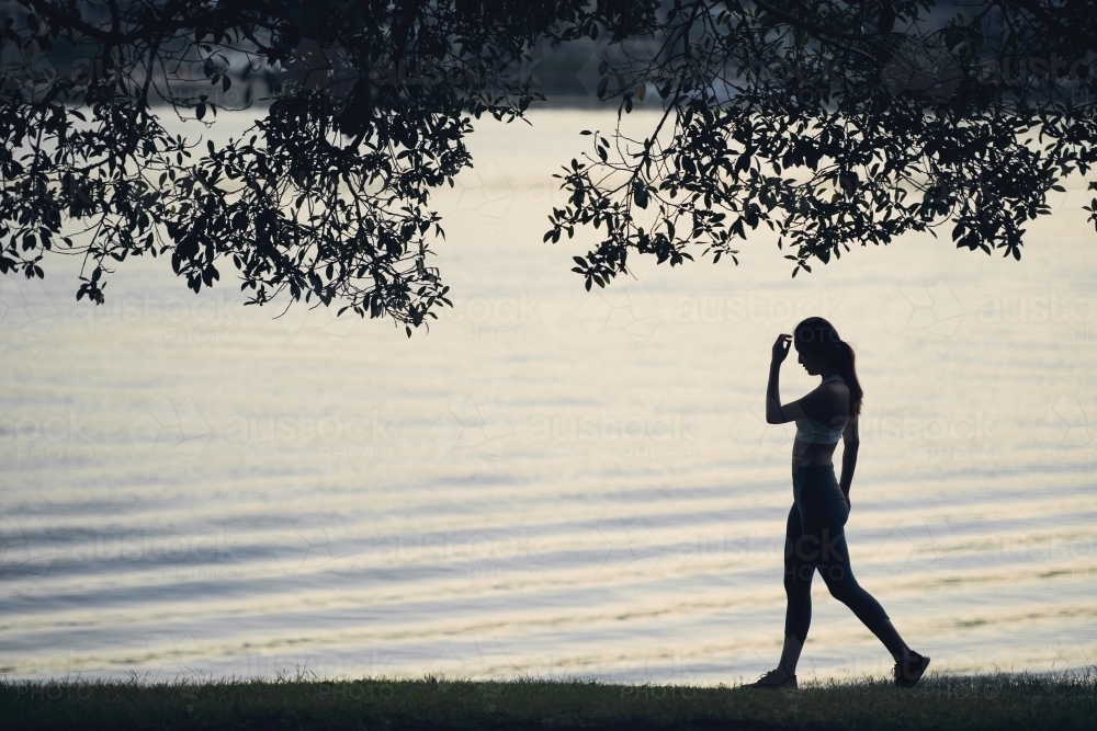Woman walking along waterside for morning exercise - Australian Stock Image