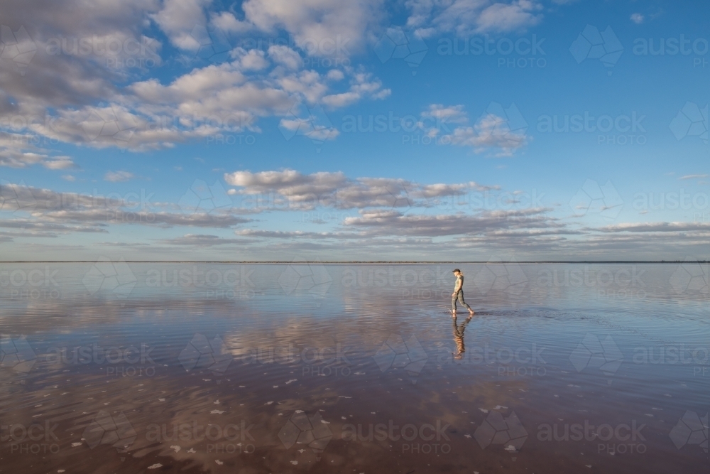 Woman walking in the distance over a salt lake with the reflections - Australian Stock Image