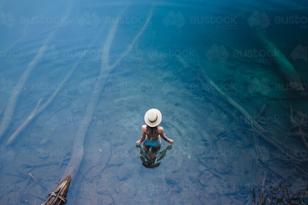 Woman walking into clear water at lake - Australian Stock Image
