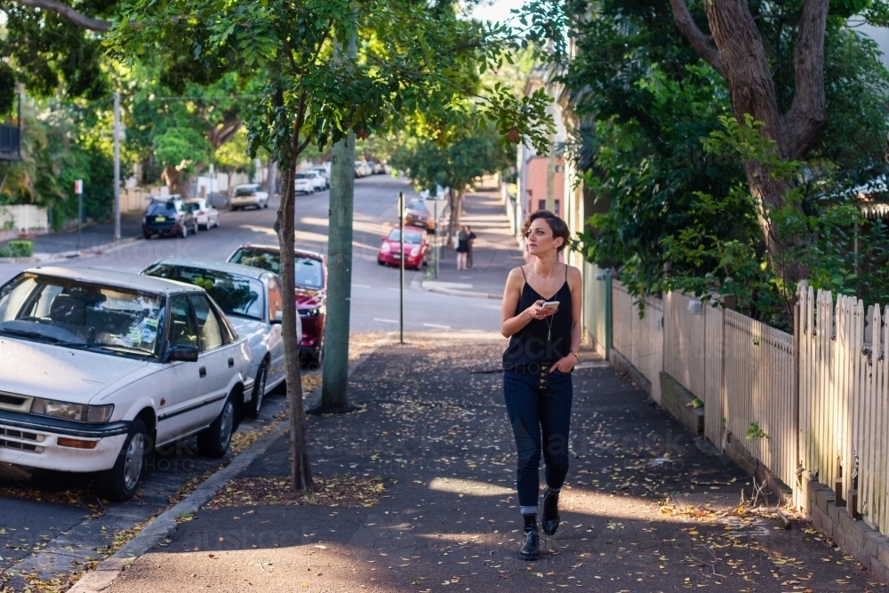 woman walking on footpath in inner city suburb - Australian Stock Image