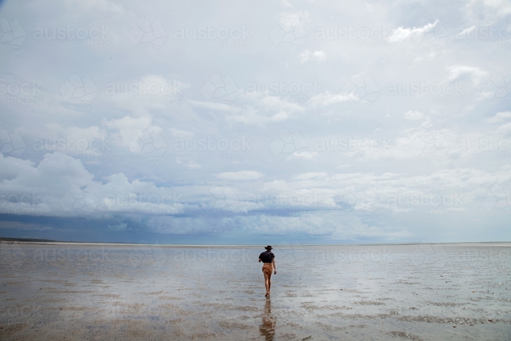 Woman walking out across shallow water - Australian Stock Image