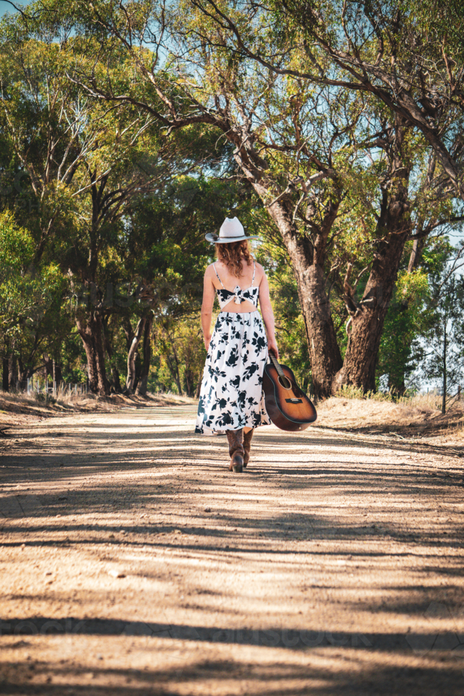 Woman walking with a guitar - Australian Stock Image