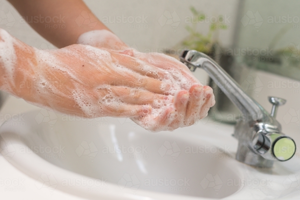 woman washing hands in basin - Australian Stock Image